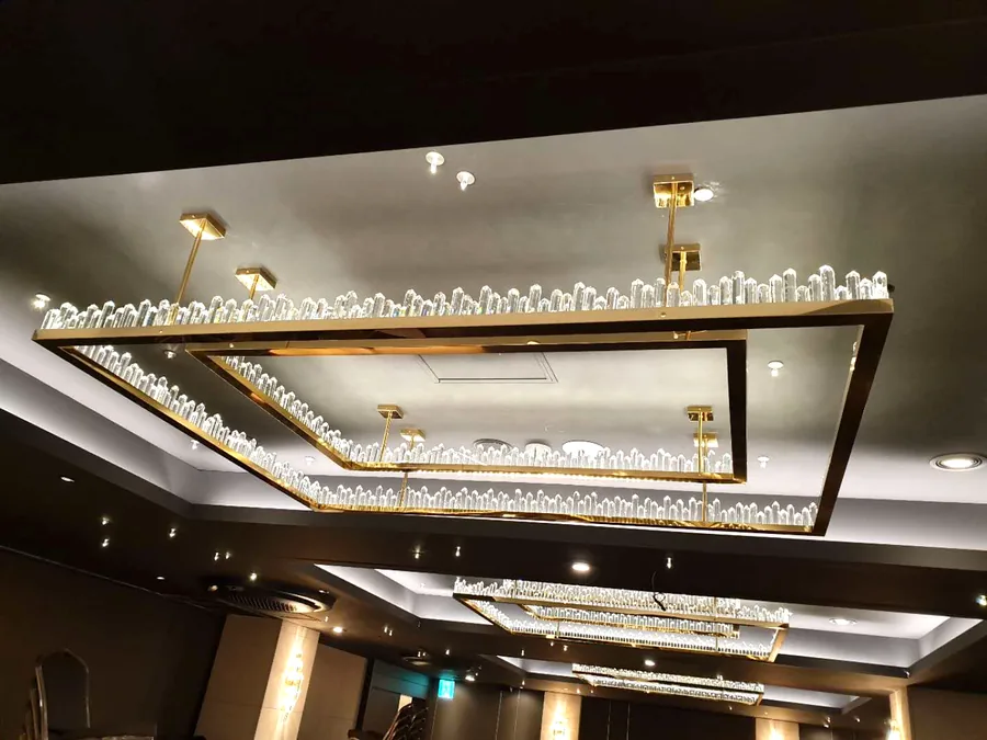 Hotel ballroom &mdash; gold rectangular crystal chandeliers receding down the ceiling